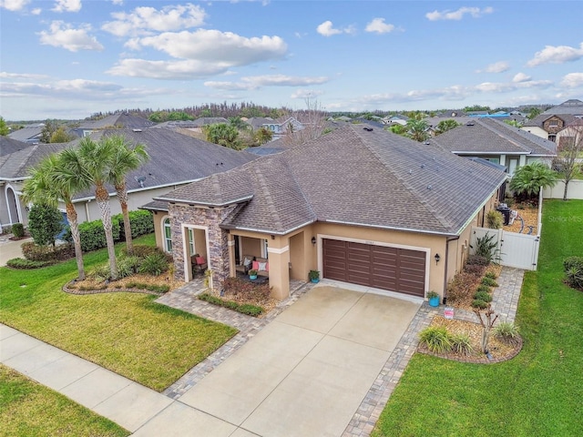 view of front of property featuring an attached garage, a gate, fence, a front lawn, and stucco siding