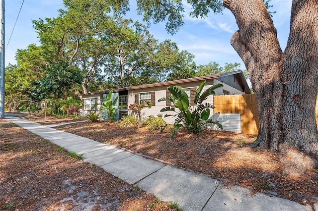 ranch-style home featuring brick siding and fence