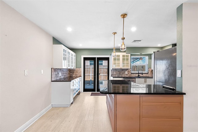 810 22nd St N, Saint Petersburg, FL 33713 - kitchen with tasteful backsplash, visible vents, light wood-style flooring, glass insert cabinets, and freestanding refrigerator