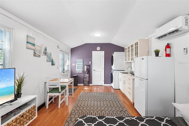 810 22nd St N, Saint Petersburg, FL 33713 - kitchen with stacked washer / dryer, a wall mounted AC, light wood-type flooring, a wealth of natural light, and freestanding refrigerator