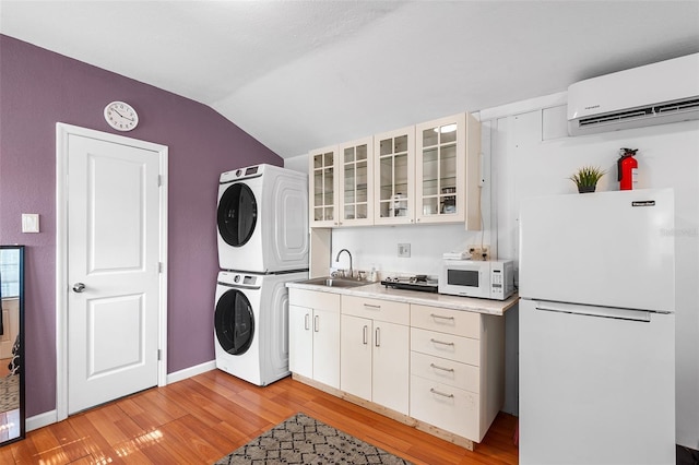 810 22nd St N, Saint Petersburg, FL 33713 - clothes washing area featuring stacked washer and dryer, baseboards, light wood-style flooring, an AC wall unit, and a sink