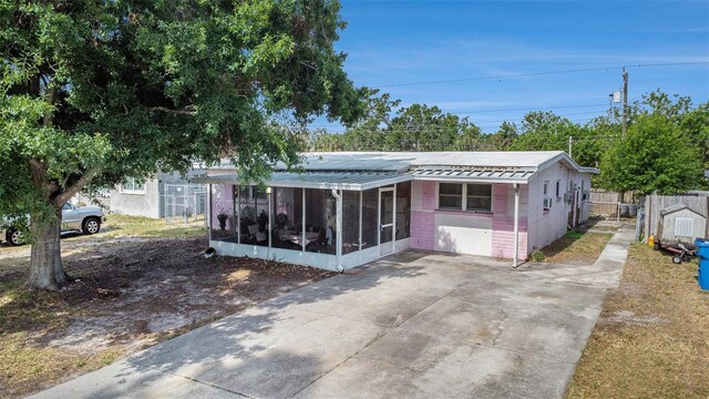 9048 94th St, Seminole, FL 33777 - view of front of property featuring fence, concrete block siding, a sunroom, metal roof, and driveway