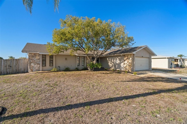 ranch-style home featuring a garage, fence, stone siding, driveway, and a front yard