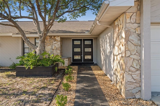 doorway to property featuring stone siding and a shingled roof