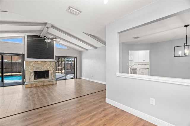 unfurnished living room featuring lofted ceiling with beams, ceiling fan with notable chandelier, wood finished floors, visible vents, and baseboards