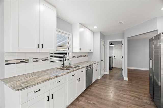 kitchen featuring light wood finished floors, tasteful backsplash, baseboards, appliances with stainless steel finishes, and a sink