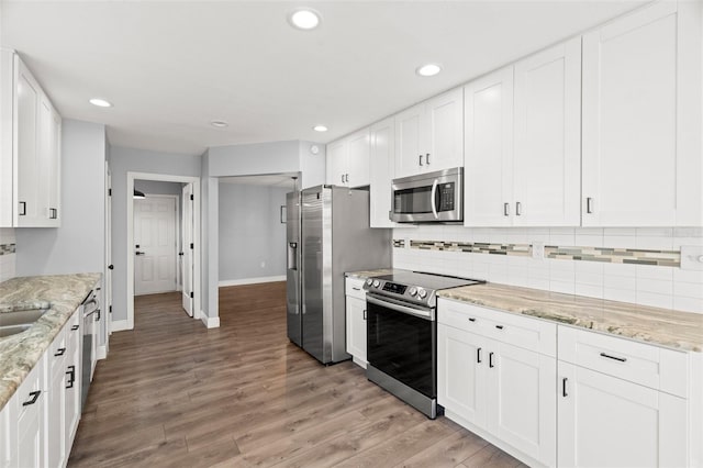 kitchen with stainless steel appliances, recessed lighting, backsplash, light wood-style flooring, and white cabinets