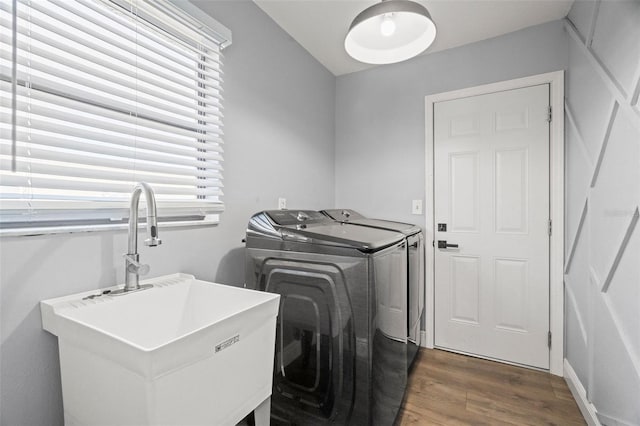 laundry room featuring laundry area, washer and clothes dryer, a sink, and dark wood-style flooring