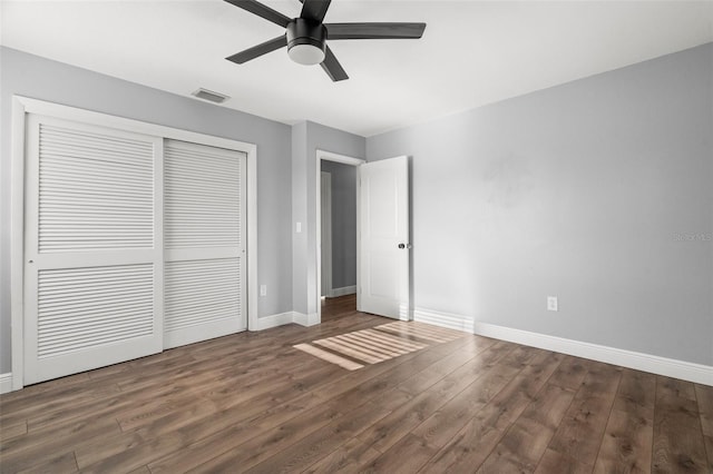 unfurnished bedroom featuring baseboards, a closet, visible vents, and wood finished floors