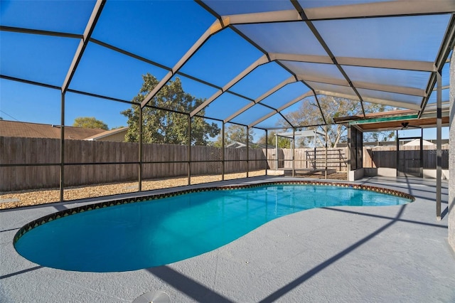 view of swimming pool featuring a fenced in pool, glass enclosure, a patio area, and a fenced backyard