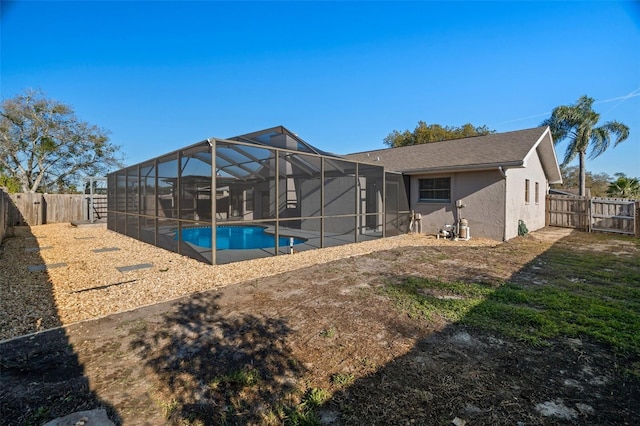 rear view of property featuring a lanai, a fenced backyard, a fenced in pool, and stucco siding