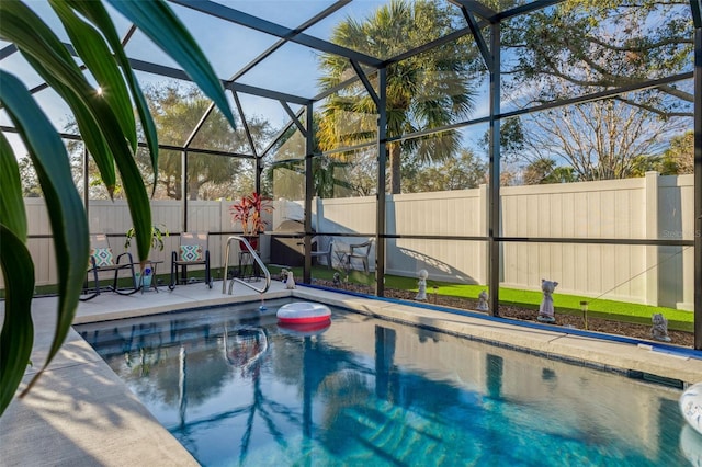 view of swimming pool with glass enclosure, a fenced backyard, and a patio