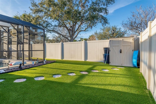 view of yard with a lanai, a storage shed, a fenced backyard, and a fenced in pool