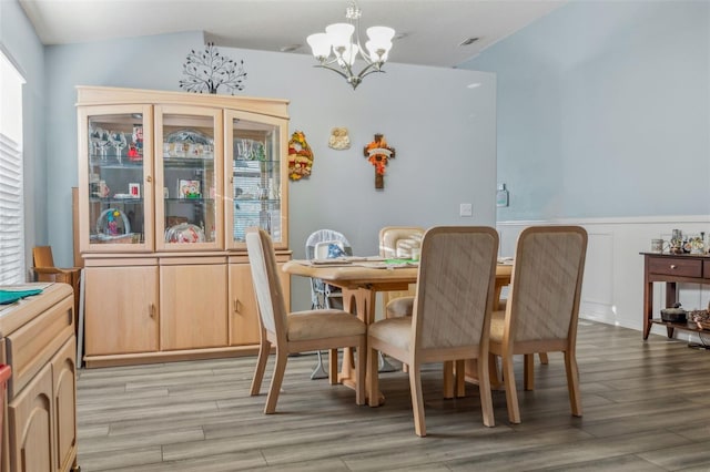 dining area featuring a wainscoted wall, light wood finished floors, and an inviting chandelier