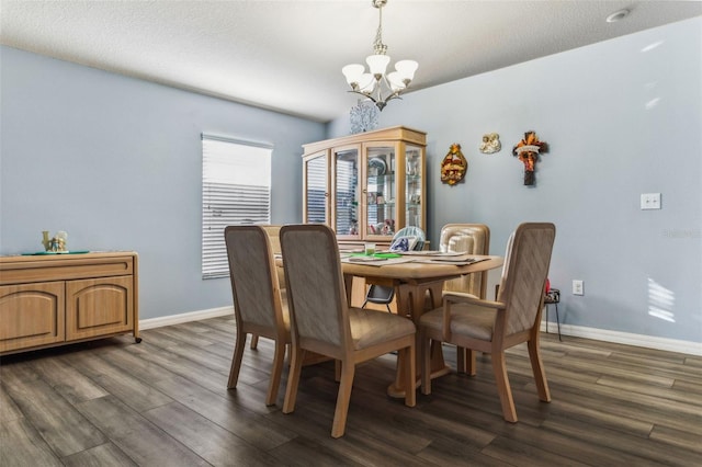 dining space with dark wood finished floors, baseboards, and an inviting chandelier
