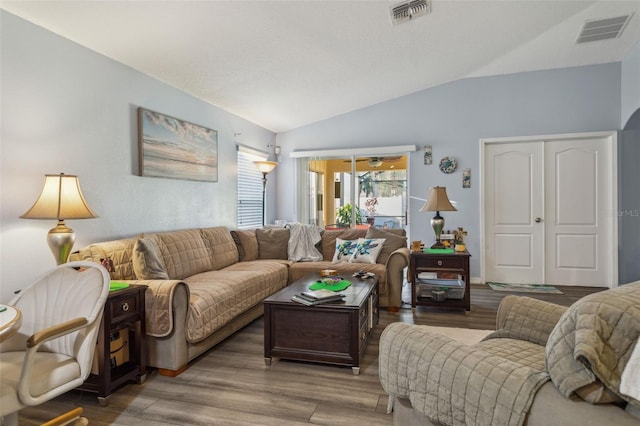 living area featuring visible vents, vaulted ceiling, and wood finished floors