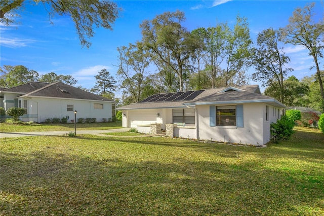 view of front facade with solar panels, a front lawn, stucco siding, driveway, and an attached garage