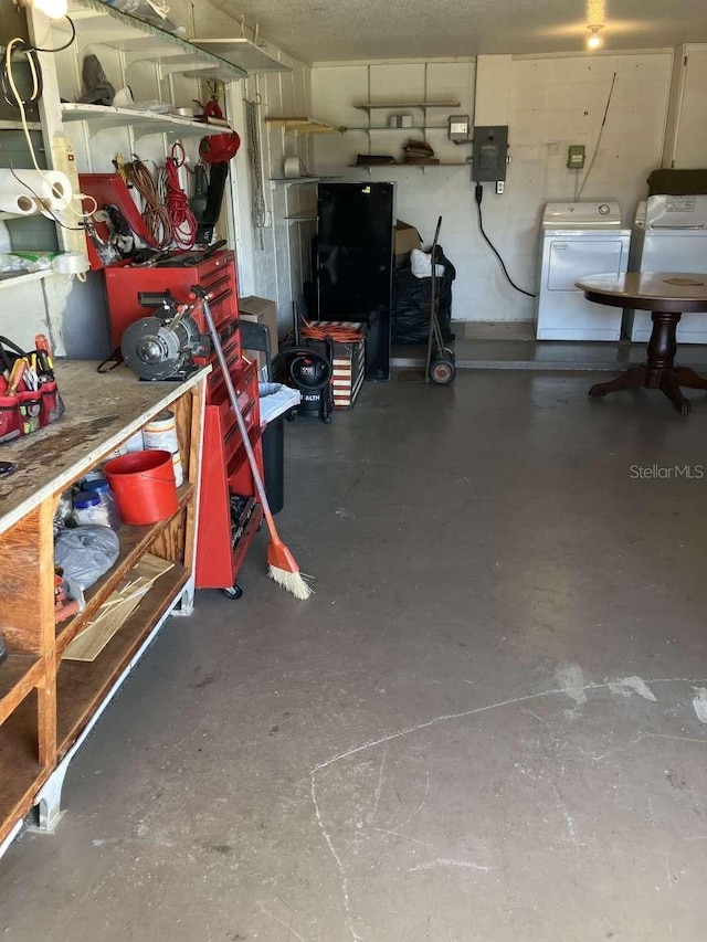 garage with electric panel, a workshop area, and separate washer and dryer