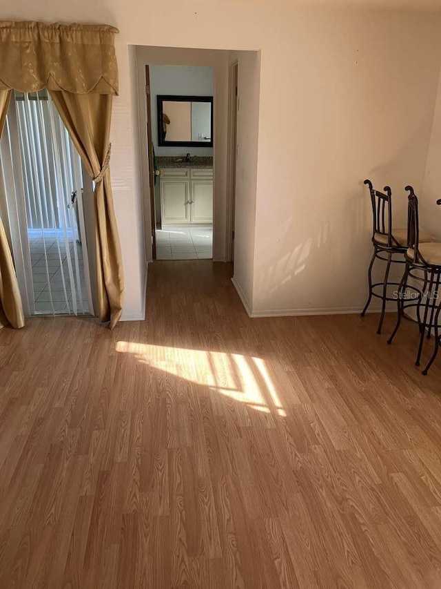 corridor with baseboards and wood finished floors