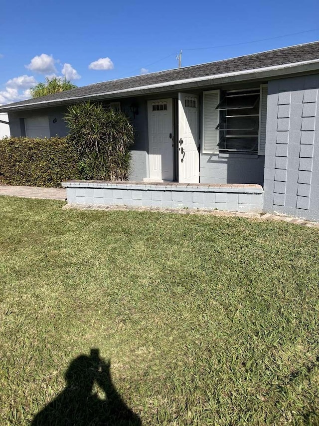 entrance to property featuring a lawn and concrete block siding