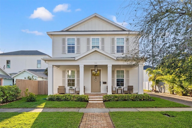 view of front of house featuring a front lawn, fence, a porch, and board and batten siding