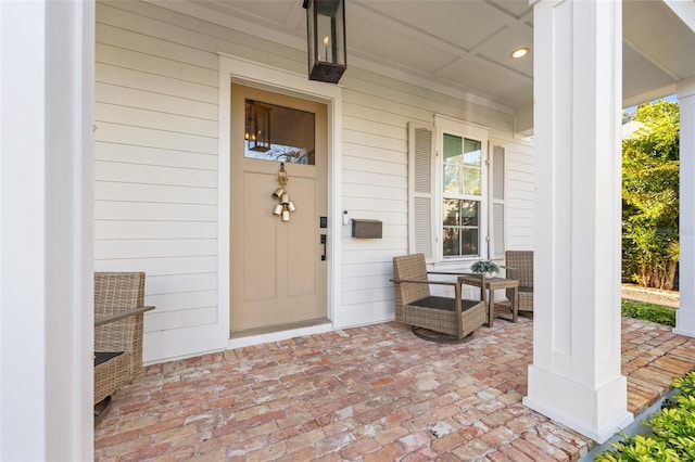 doorway to property with covered porch and brick siding