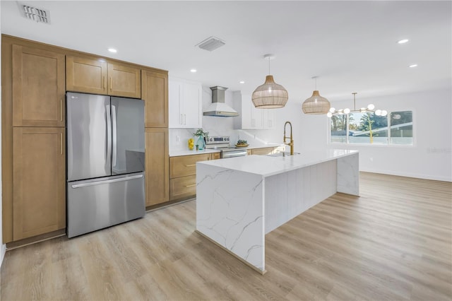 kitchen featuring light wood finished floors, wall chimney exhaust hood, visible vents, and appliances with stainless steel finishes