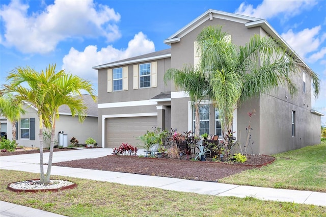 traditional-style home with a garage, a front yard, driveway, and stucco siding