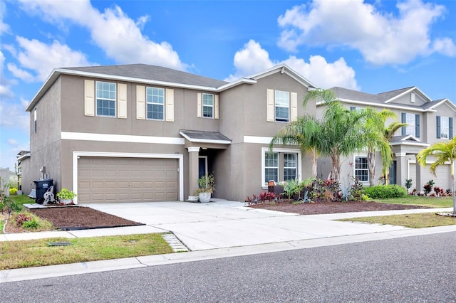 traditional-style home featuring concrete driveway, an attached garage, and stucco siding