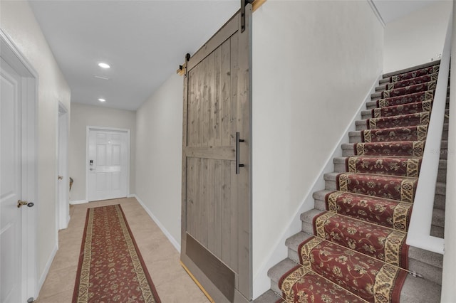 staircase with tile patterned floors, a barn door, baseboards, and recessed lighting