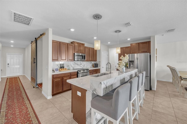 kitchen featuring a barn door, visible vents, stainless steel appliances, and a sink