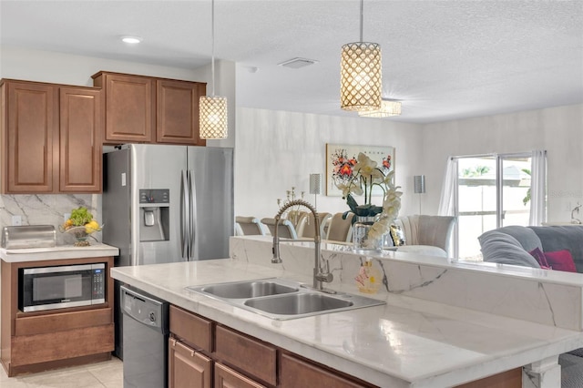 kitchen with visible vents, open floor plan, a kitchen island with sink, stainless steel appliances, and a sink