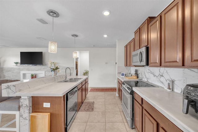 kitchen featuring brown cabinets, a sink, stainless steel appliances, backsplash, and light tile patterned flooring