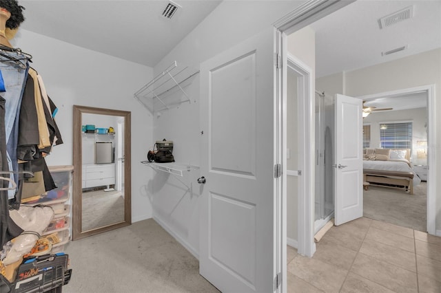 walk in closet featuring light tile patterned flooring, visible vents, and light colored carpet