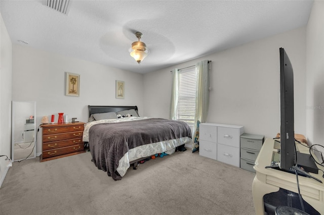 carpeted bedroom with a textured ceiling, visible vents, and a ceiling fan