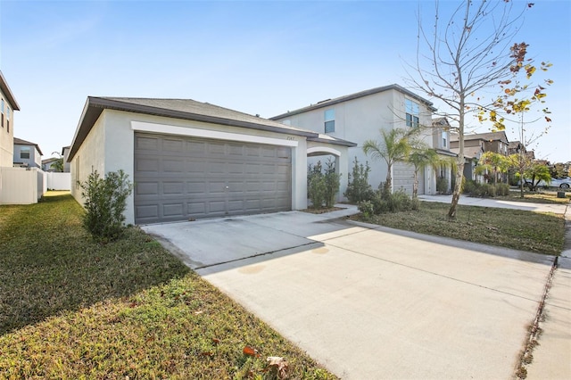 view of front of home with a garage, concrete driveway, stucco siding, fence, and a front yard