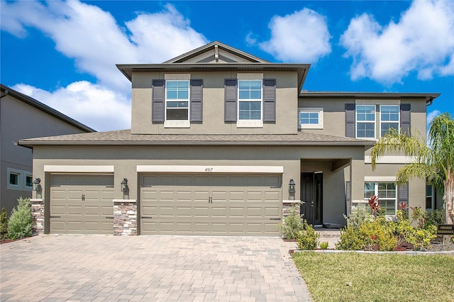 view of front of property featuring decorative driveway, stone siding, and stucco siding