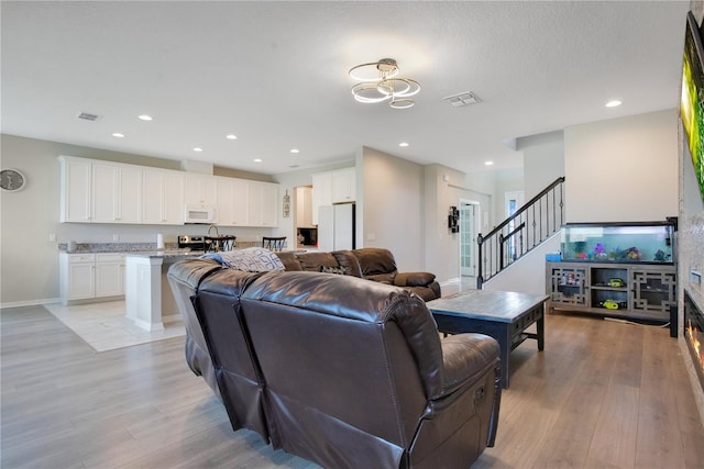 living area with recessed lighting, visible vents, and light wood-type flooring