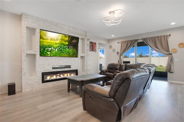 living room featuring recessed lighting, light wood-style floors, and a large fireplace