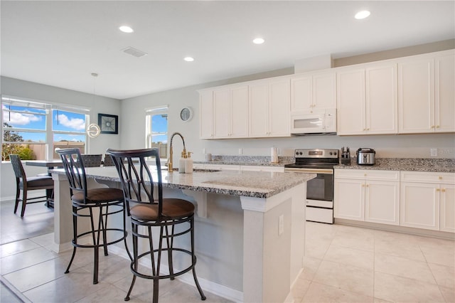 kitchen with white microwave, visible vents, recessed lighting, a sink, and stainless steel range with electric cooktop