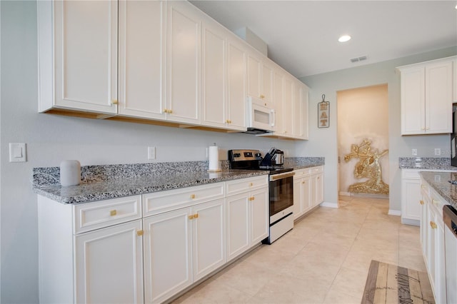 kitchen featuring white microwave, visible vents, light stone countertops, stainless steel range with electric cooktop, and white cabinetry