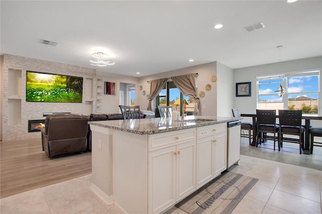 kitchen with light tile patterned flooring, visible vents, dishwasher, and a sink