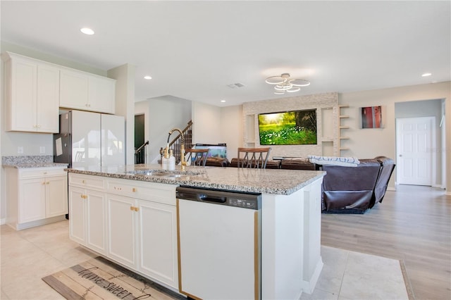 kitchen featuring open floor plan, an island with sink, white appliances, white cabinetry, and a sink