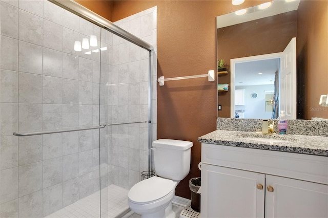 bathroom with toilet, a stall shower, vanity, and a textured wall