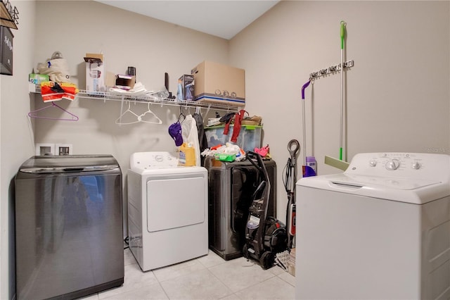 clothes washing area with light tile patterned flooring, washing machine and dryer, and laundry area