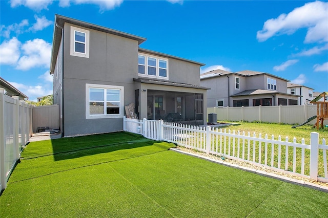 rear view of property featuring stucco siding, a yard, a fenced backyard, and a sunroom