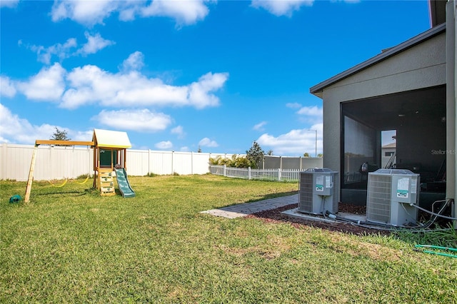 view of yard featuring central air condition unit, a fenced backyard, and a playground