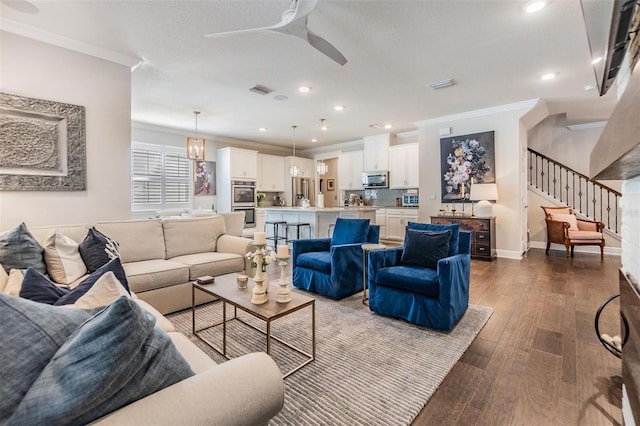 living area with stairway, a ceiling fan, dark wood-style flooring, and crown molding