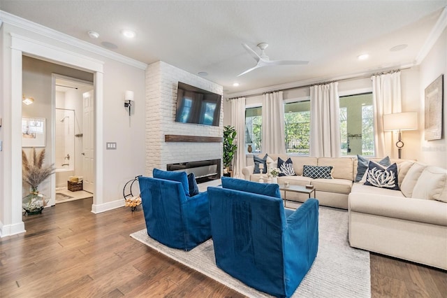 living room with baseboards, wood finished floors, a brick fireplace, and ornamental molding