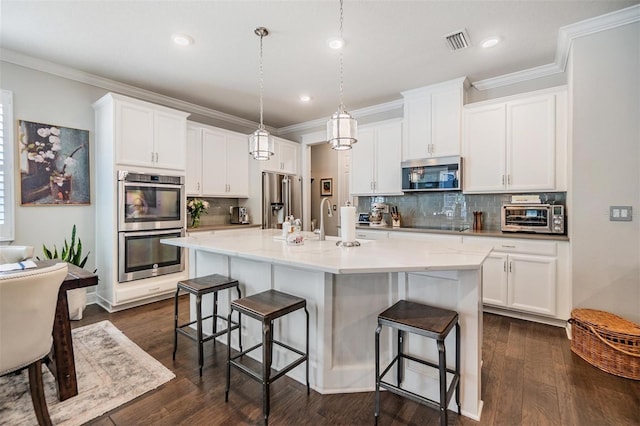 kitchen with visible vents, a breakfast bar, dark wood finished floors, stainless steel appliances, and crown molding